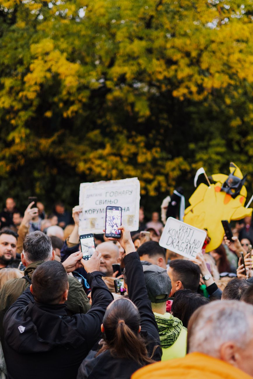 Okupljeni ljudi na protestu s transparentima i mobilnim telefonima, Belgrad.