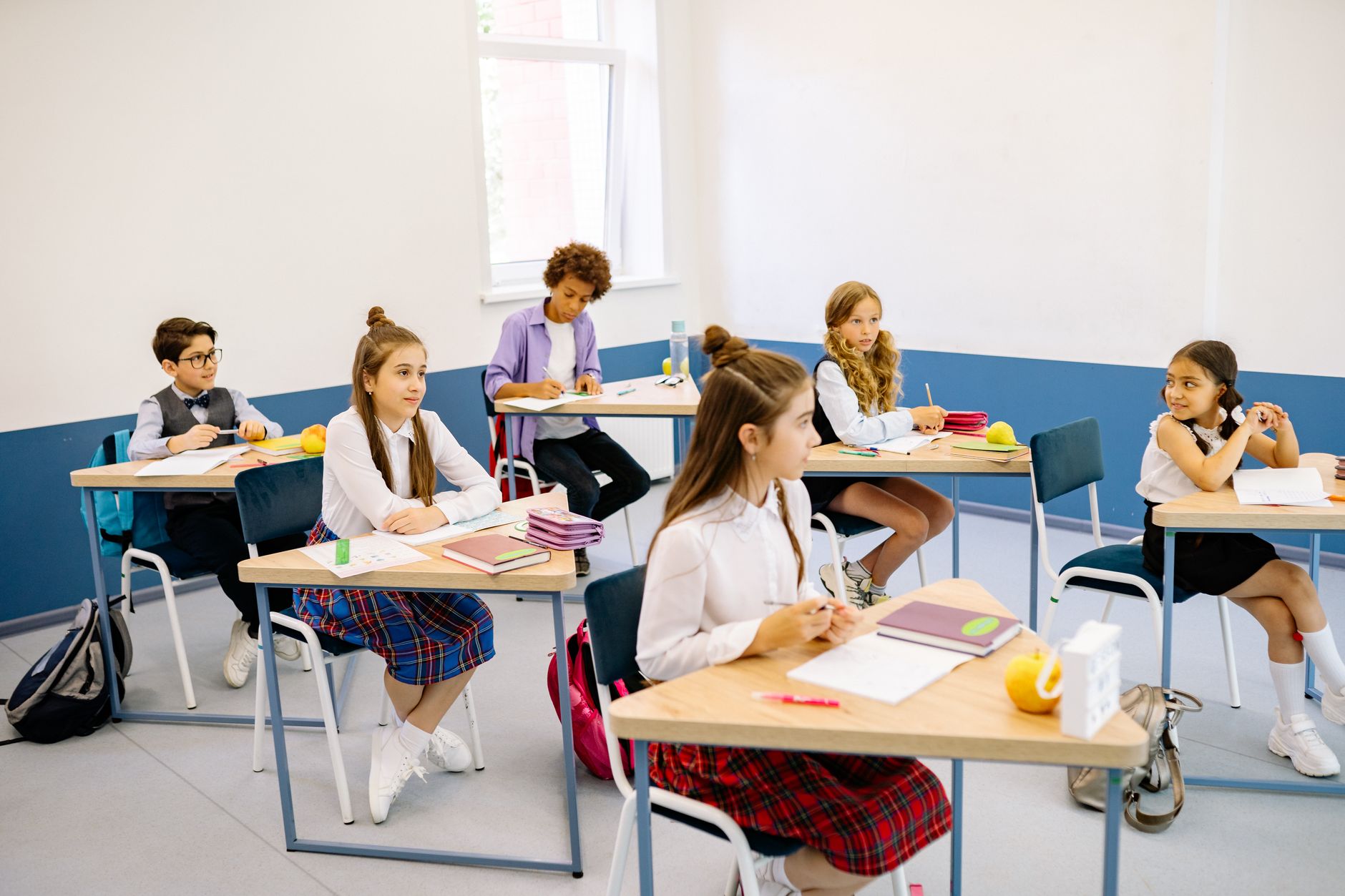 Elever sitter uppmärksamma under en lektion i ett ljust klassrum.