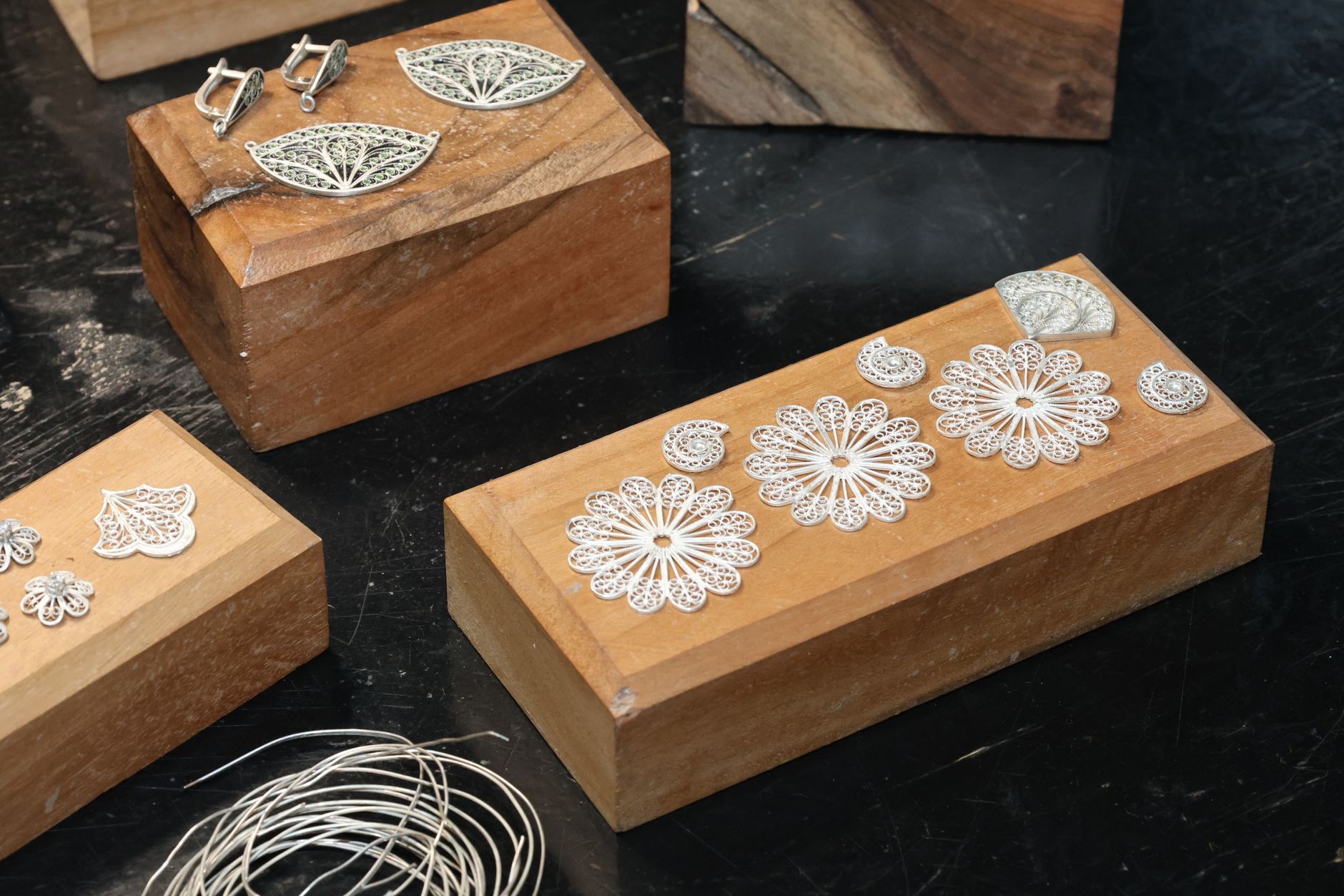 Närbild på detaljrika och intrikata silversmycken i filigran på träklossar.