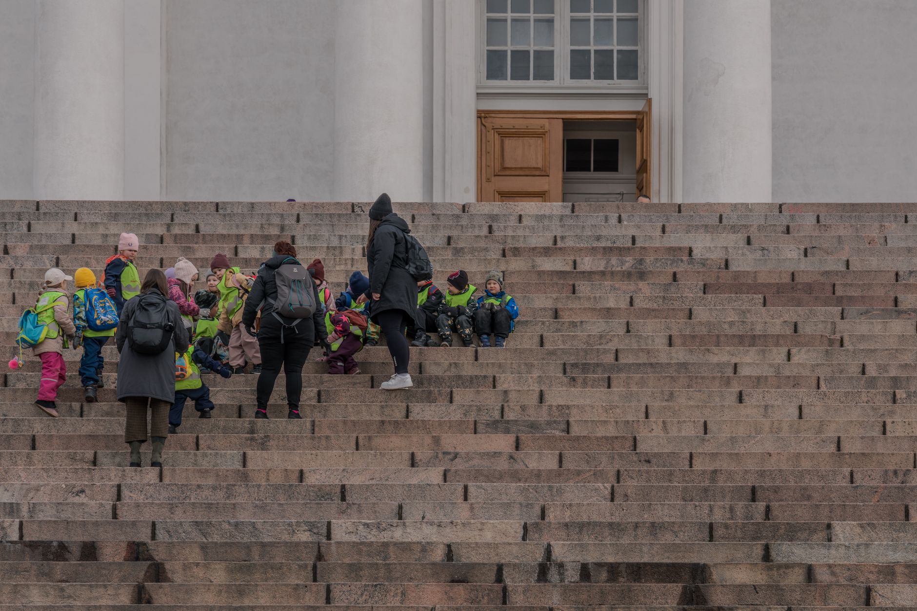 En grupp barn och vuxna står på trappan till Helsingfors domkyrka under en utflykt.