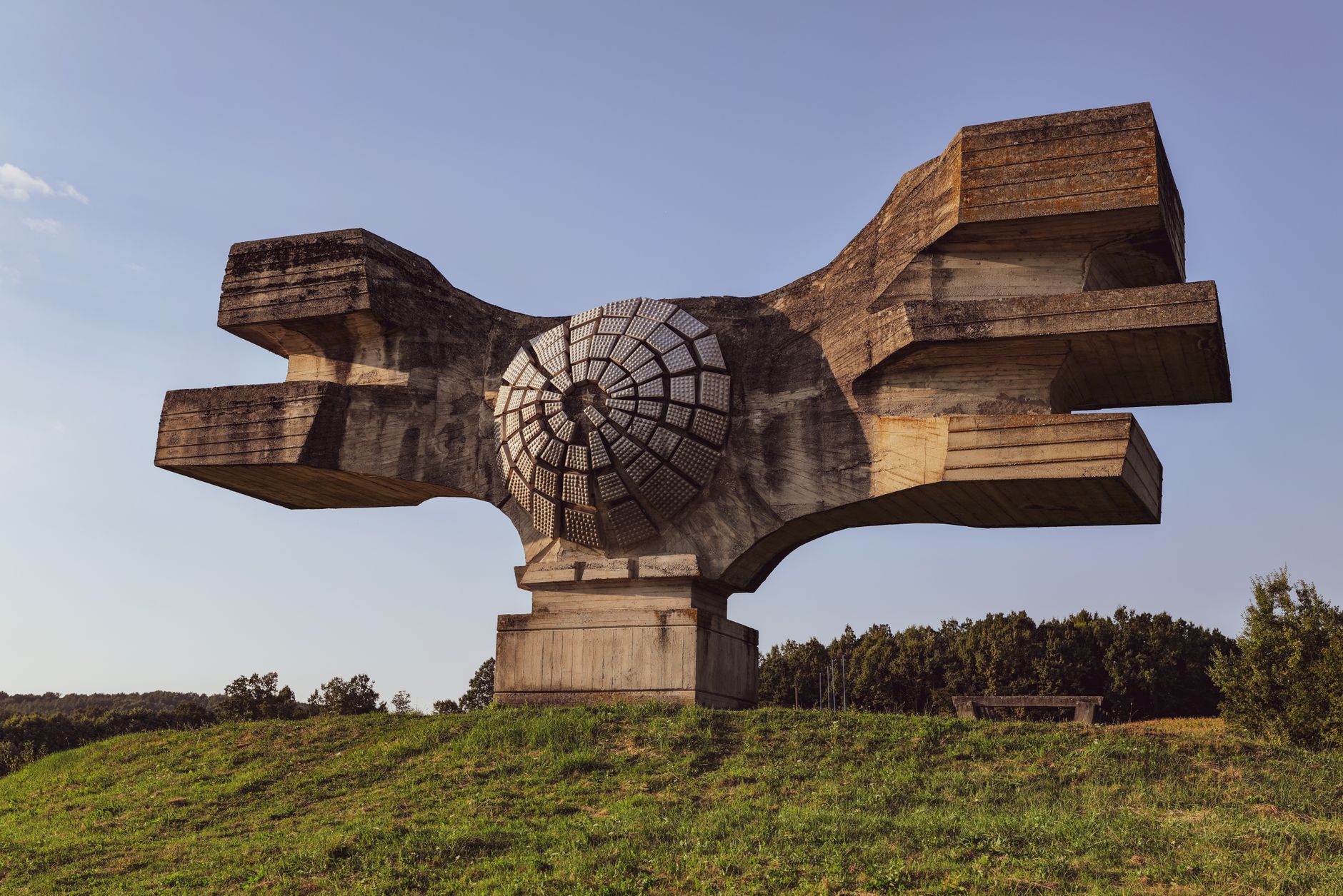 Ett abstrakt och futuristiskt betongmonument på en grön kulle i Kroatien.