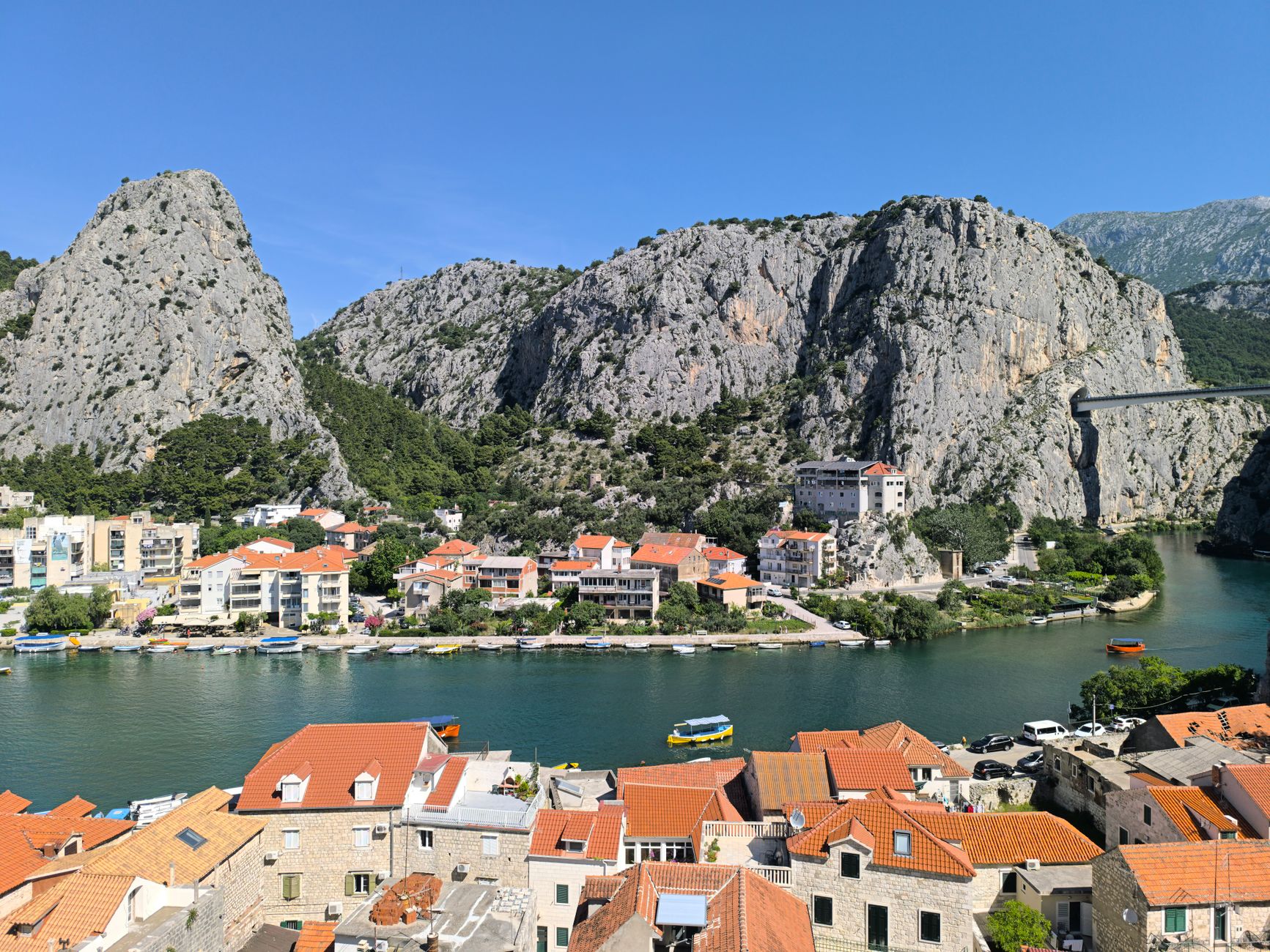 Vy över staden Omiš med flod, hus och berg i bakgrunden.