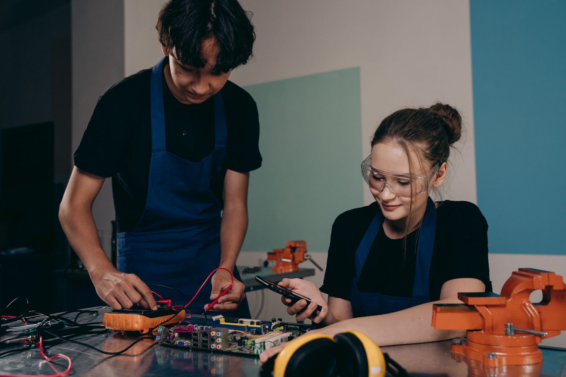 Två personer fokuserar på att koppla kretskort och arbeta med elektronik i ett laboratorium.