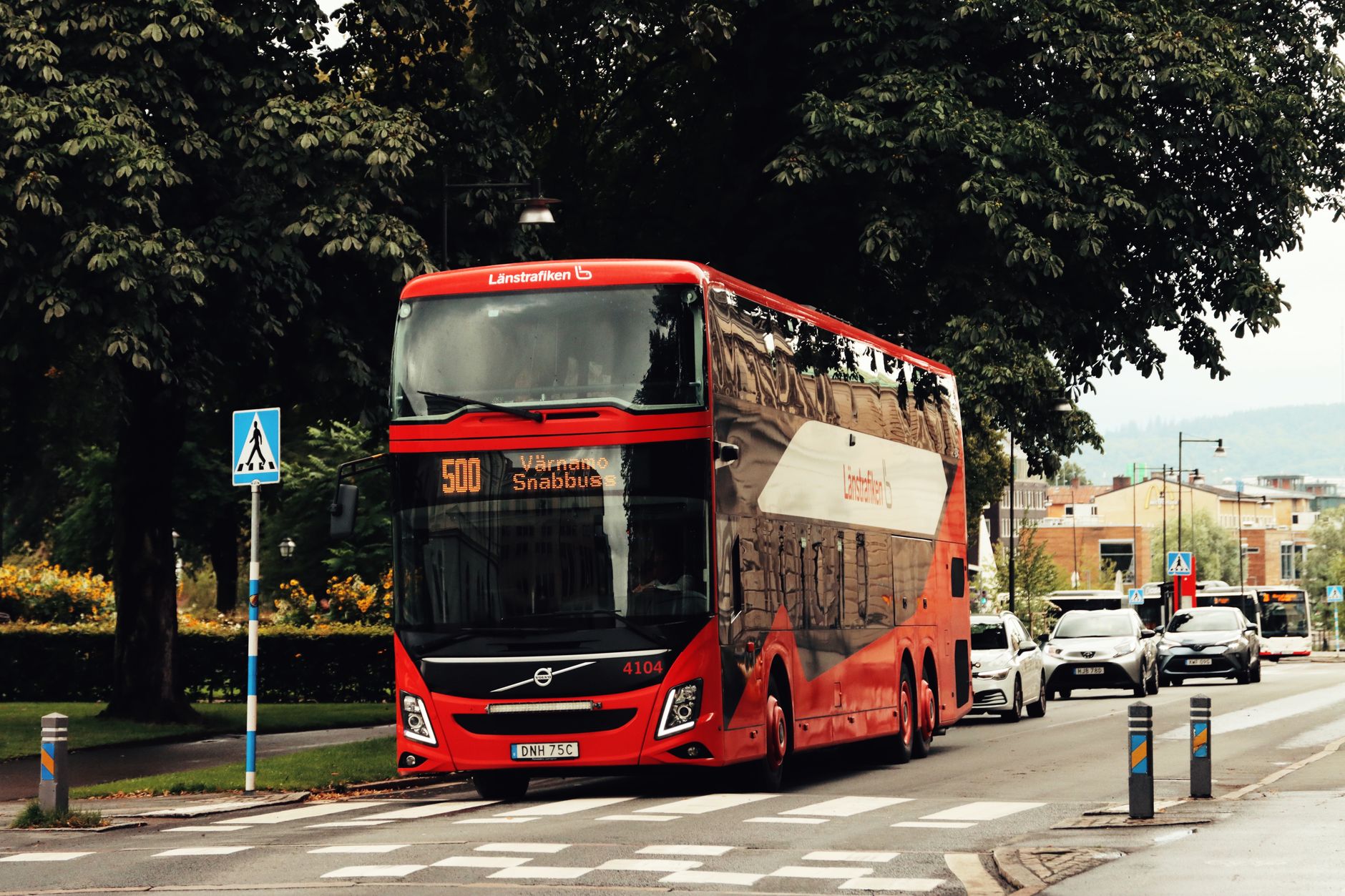 En röd dubbeldäckad buss av märket Volvo kör på en gata i Jönköping.