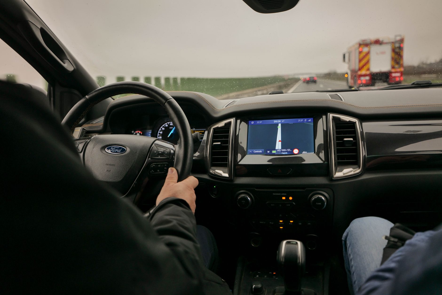 Utsikt inifrån en bil som kör på en motorväg med bilens navigationssystem synligt.
