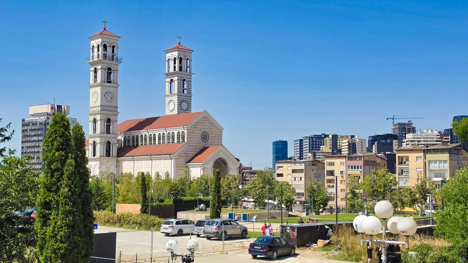 Vy över Pristina i Kosovo med Sankta Teresa-katedralen och stadens bebyggelse under en blå himmel.