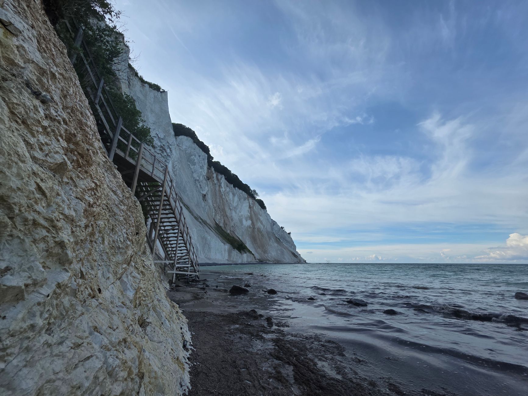 En lång trätrappa leder nerför de branta vita kritklipporna vid Møns Klint mot havet.