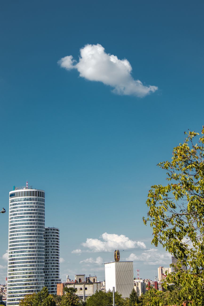En modern skyskrapa i Belgrad mot en blå himmel med vita moln.
