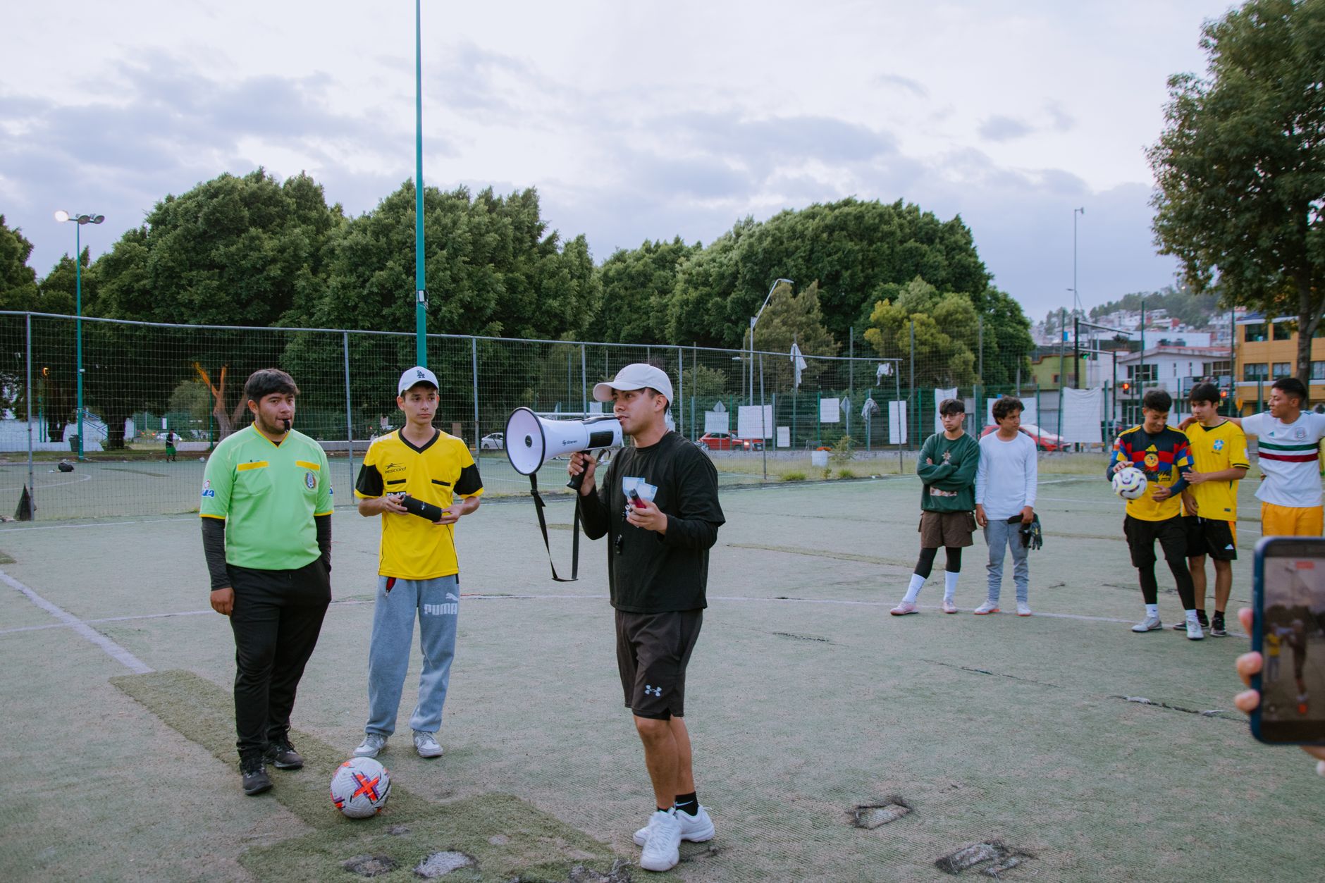 Tränare ger instruktioner till unga fotbollsspelare på en plan utomhus.