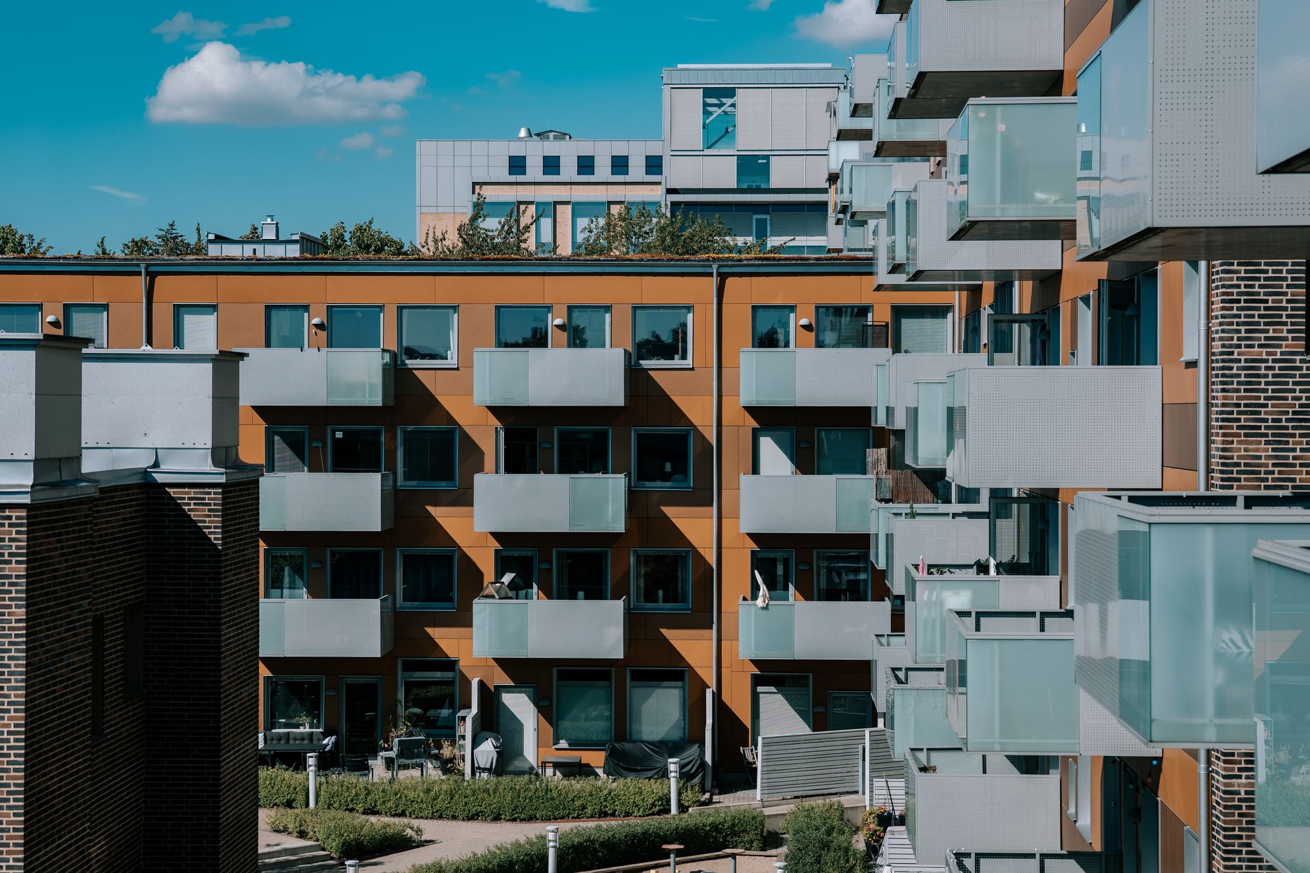 Ett modernt flerbostadshus med balkonger under en blå himmel i Lund.